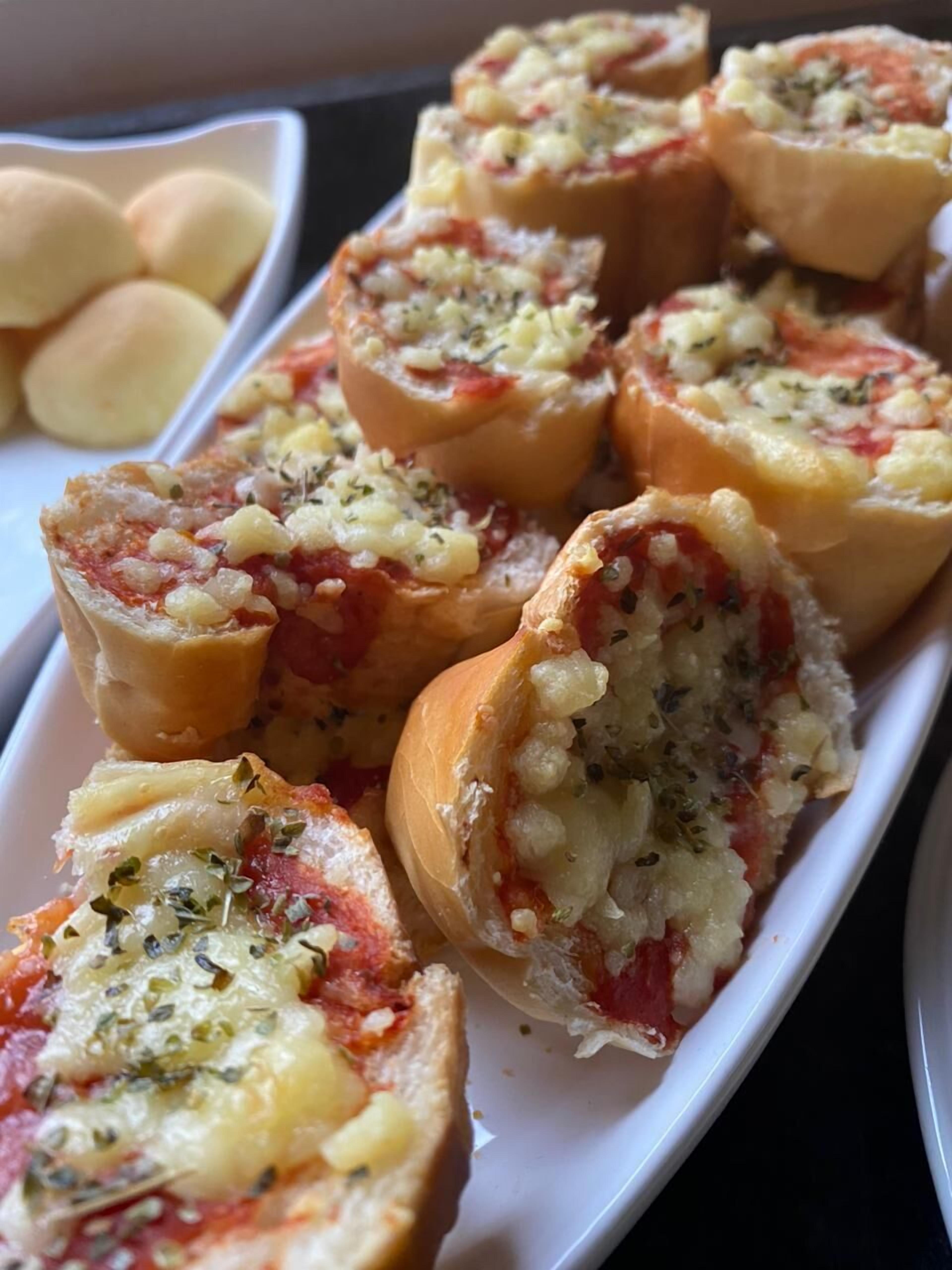 Un plato de bollos rellenos con un relleno a base de tomate, adornados con hierbas.