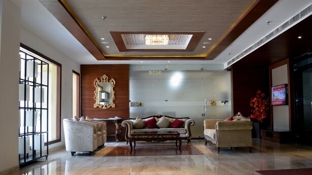 A spacious lobby with a large mirror, a sofa, and a coffee table. - Royal Inn (Muktsar)