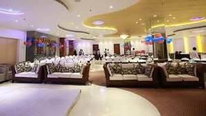 A spacious indoor venue with multiple seating areas, including sofas and round tables, arranged for events or gatherings. - Royal Inn (Muktsar)