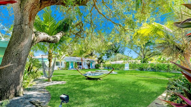 A well-maintained garden with a hammock, a fountain, and a pathway leading to a house. - Cottages El Portal (Miami)