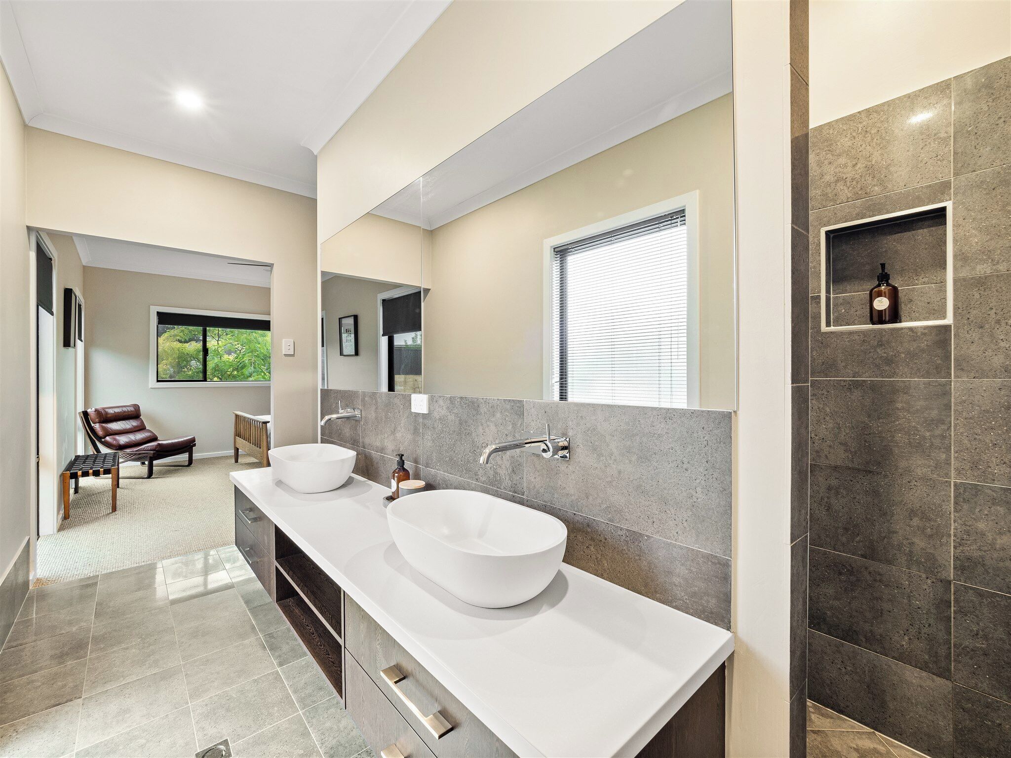 Un bagno moderno con due ampi lavabi bianchi, uno specchio e una finestra con persiane.