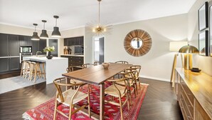 Une cuisine moderne avec des meubles de couleur sombre, un îlot central et des luminaires suspendus.