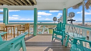 Una terraza techada con mobiliario de madera y vista despejada a la playa y el océano.