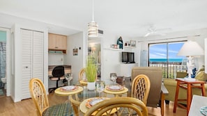 Um espaço compacto com área de refeições, kitchenette e varanda com vista para o mar.