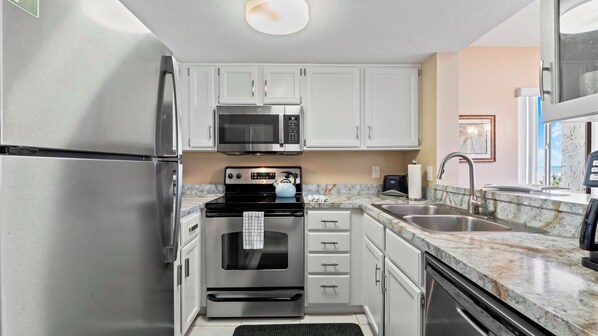 A compact kitchen with stainless steel appliances, white cabinets, and a granite countertop. - St. Augustine Oceanfront Condo, Resort Pools, Tennis & Direct Beach Access (St. Augustine)