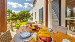 Un comedor al aire libre con una mesa de madera preparada para dos personas, rodeada de sillas de mimbre.