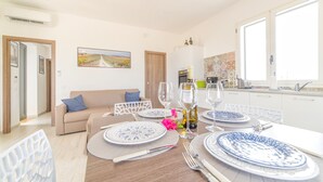 Un comedor con una mesa dispuesta para cuatro, un sofá y una cocina al fondo.