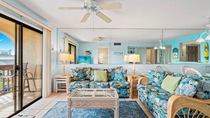 A spacious living room with a large sofa set, a coffee table, and a ceiling fan. - Beautiful Ocean-View St. Augustine Condo • Steps from Beach (St. Augustine)