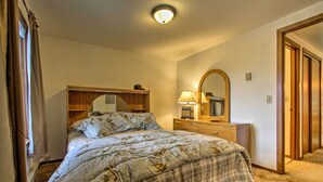 A bedroom with a bed, a dresser, a mirror, and a window with curtains. - Cozy Angler's Apt - Steps to Trout Fishing River! (Columbus)