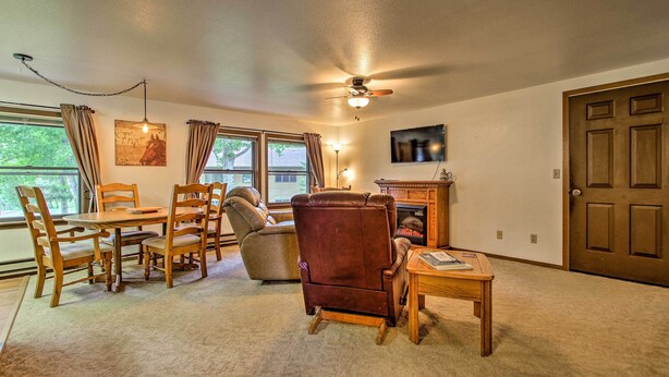 A living room with a fireplace, a ceiling fan, and a television mounted on the wall. - Cozy Angler's Apt - Steps to Trout Fishing River! (Columbus)