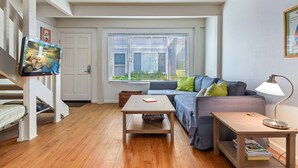 A cozy living room with a wooden floor, a sofa, a coffee table, and a TV on a stand. - Best Deal in Carpinteria! (Carpinteria)