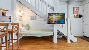 A room with a bed, a TV on a stand, a staircase, and a door labeled "LOT 7". - Best Deal in Carpinteria! (Carpinteria)