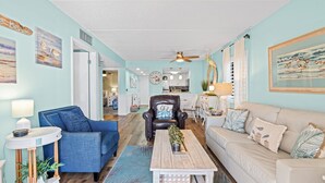 A living room with a blue couch, a beige sofa, a wooden coffee table, and a leather armchair. - Poolside 2BR Condo in Oceanfront Resort - Sleeps 6, Steps to Beach (St. Augustine)