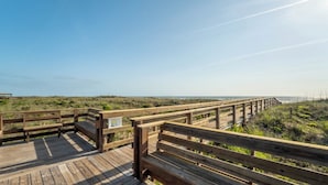 Un muelle de madera que conduce a una playa, con cielo despejado.