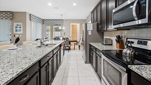 A modern kitchen with granite countertops, stainless steel appliances, and dark cabinetry.
