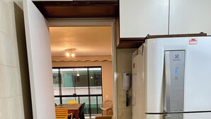 Una cocina con un refrigerador blanco, piso de baldosas y un comedor con sillas y una mesa.
