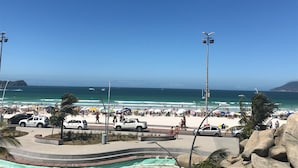 Una playa con una carretera, coches y gente.