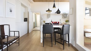 Una cocina moderna con armarios blancos, techo de madera y un comedor con sillas negras y una mesa blanca.