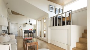 Un amplio espacio de sala con un sofá, una mesa de centro y una escalera que lleva a un nivel superior.