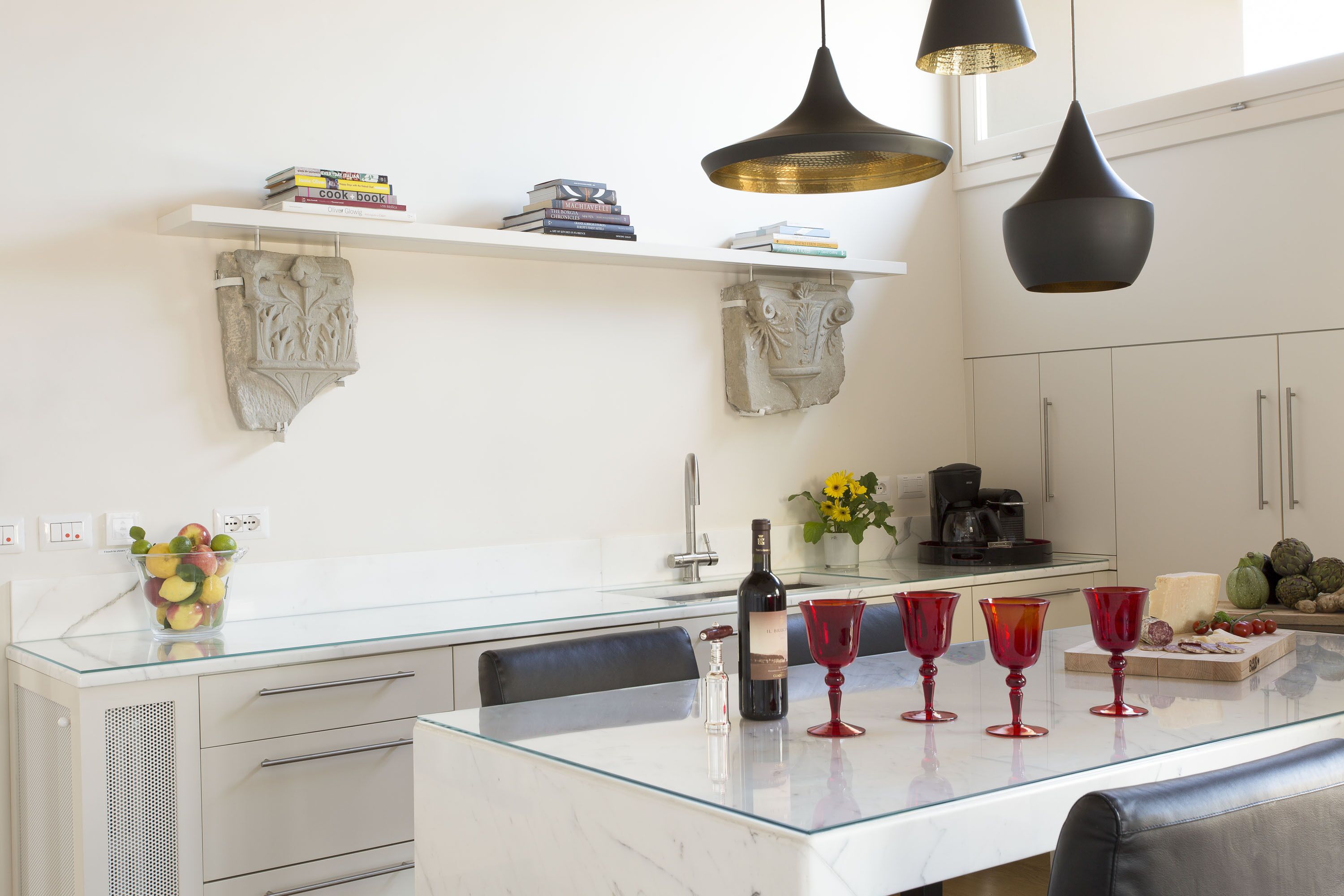 A modern kitchen with a marble countertop, a glass island, and a built-in wine cooler.