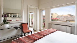 Un dormitorio con una cama, una silla, un escritorio y un ventanal grande.