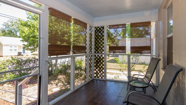 A covered porch with a view of the backyard, featuring a seating area with chairs and a table. - Seabird Shack: Dog Friendly, Downtown Pensacola! (Pensacola)