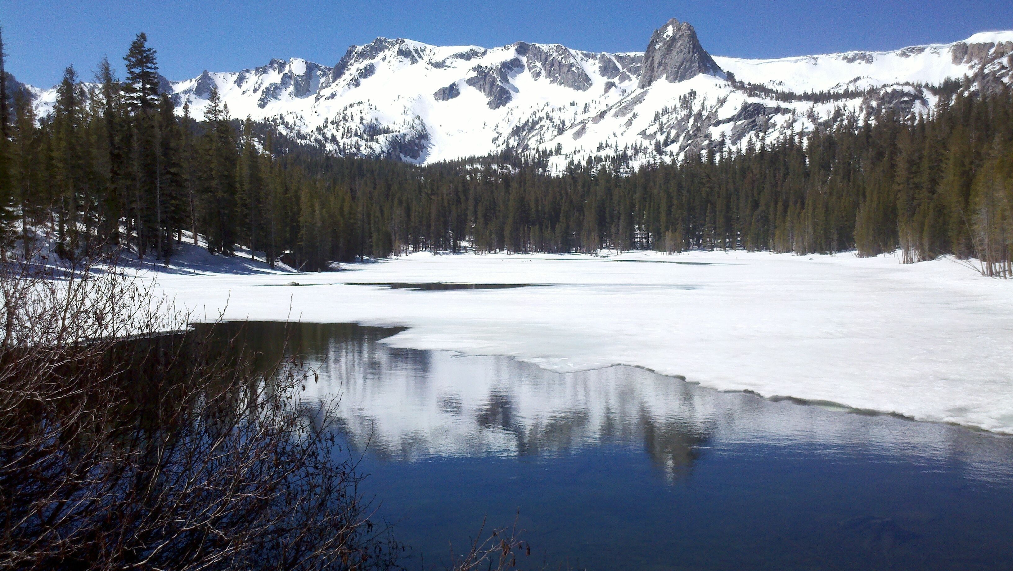 Un lac paisible, entouré de montagnes enneigées et de forêts denses.