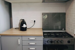 A kitchen with a gas stove, a coffee maker, and a white tiled backsplash. - Vintage Beach and Golf Villa (Costa da Caparica)