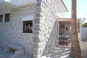 A stone building with a window, a bench, and a table with chairs outside. - Vintage Beach and Golf Villa (Costa da Caparica)