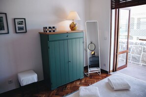 A room with a teal cabinet, a standing mirror, a lamp, and a bed with white linens. - Vintage Beach and Golf Villa (Costa da Caparica)