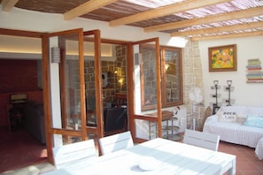 A room with a stone wall, a wooden ceiling, a white sofa, and a table with chairs. - Vintage Beach and Golf Villa (Costa da Caparica)