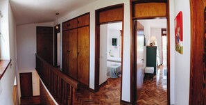 A hallway with wooden doors and a herringbone floor leading to a bedroom with a bed and a nightstand. - Vintage Beach and Golf Villa (Costa da Caparica)