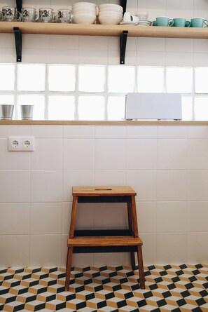 A kitchen with a wooden stool, white tiles, and a window with a view. - Vintage Beach and Golf Villa (Costa da Caparica)