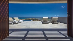 Un balcone con due poltrone vista mare e cielo azzurro.