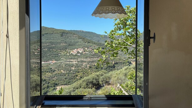 Ein Balkon mit freiem Blick auf eine gebirgige Landschaft, einer Spitzendecke und einer Tür mit Griff.