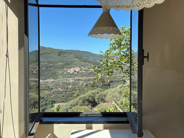 Un balcón con vista despejada a un paisaje montañoso, un candelabro de encaje y una puerta con picaporte.