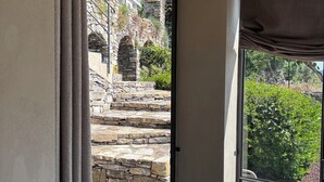 Ein Zimmer mit einer Schiebetür aus Glas, die zu einer Steintreppe und einem Sitzbereich im Freien führt.