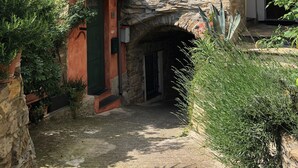 Ein Steinhaus mit einem kleinen Rundbogenportal, einem Ziegeldach und einem Blumentopf nahe dem Eingang.