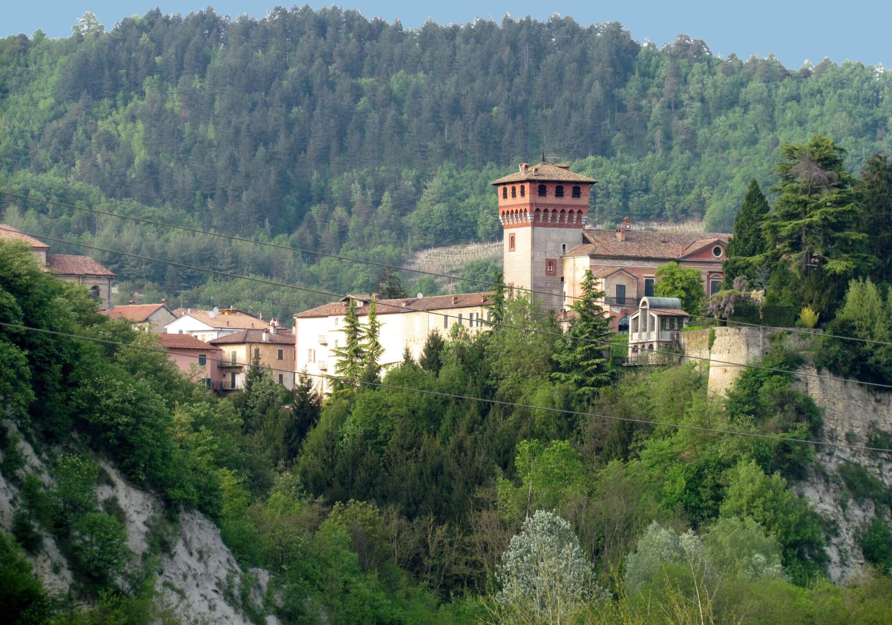 A hillside village with traditional architecture, including a prominent tower and stone buildings.