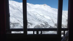 Blick aus dem Fenster auf einen mit Schnee bedeckten Berg.