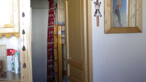 Ein Korridor mit einer Holztür, einem kleinen Tisch mit roten Kissen und einem Poster an der Wand.