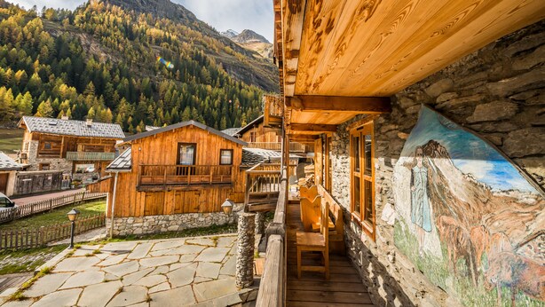 Eine Holzhütte mit Steinmauern, einem Balkon und Blick auf die Berge.