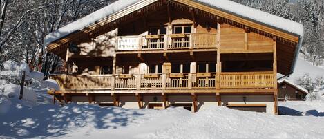 Una cabaña de madera con balcón, rodeada de nieve.