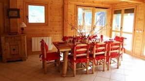 A wooden interior with a dining table and chairs, a radiator, and a window with a view. - Luxury chalet in the Savoie, typical of the Beaufortain area -classified 4 (Villard-sur-Doron)