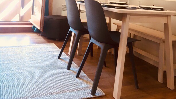 Un comedor con una mesa dispuesta para dos personas, un televisor de pantalla plana en la pared y un cuadro de montañas.