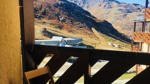 Un balcón con sillas de madera, con vistas a un paisaje montañoso.