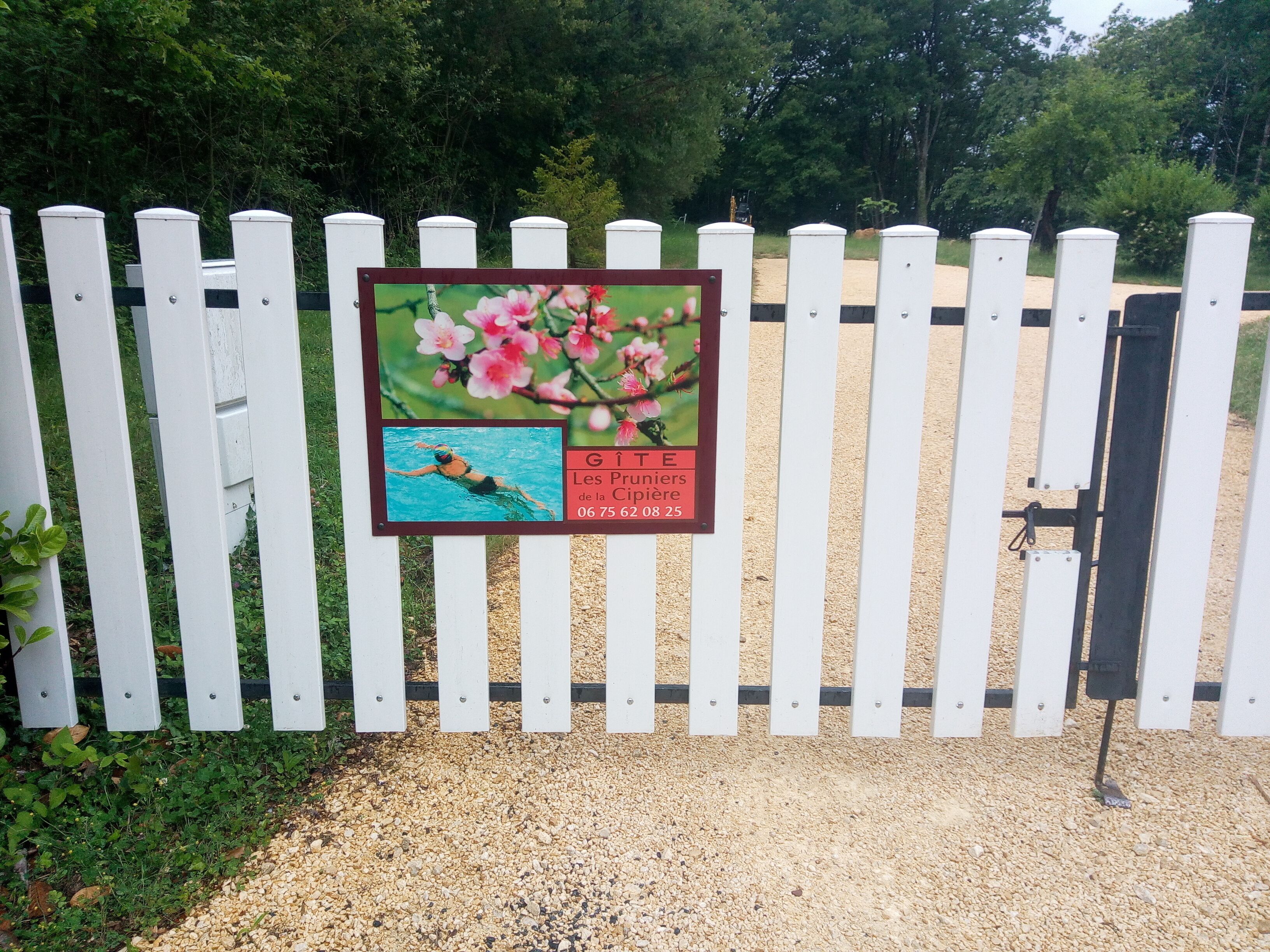 A white picket fence with a signboard displaying a swimming pool and flowers.