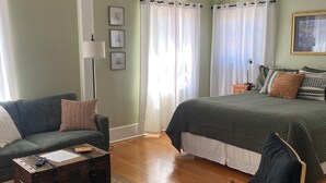 Un dormitorio con cama, una silla, un sofá, un aparador y un ventilador de techo.