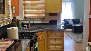 Una cocina con armarios de madera, estufa y ventana con persianas.