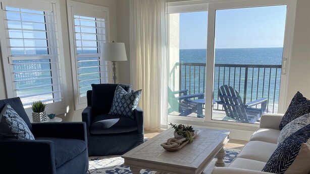 A living room with a view of the ocean, featuring a sofa, a coffee table, and a patterned rug. - Sweeping Vue of the Gulf of Mexico, 30 steps to beach (Mexico Beach)